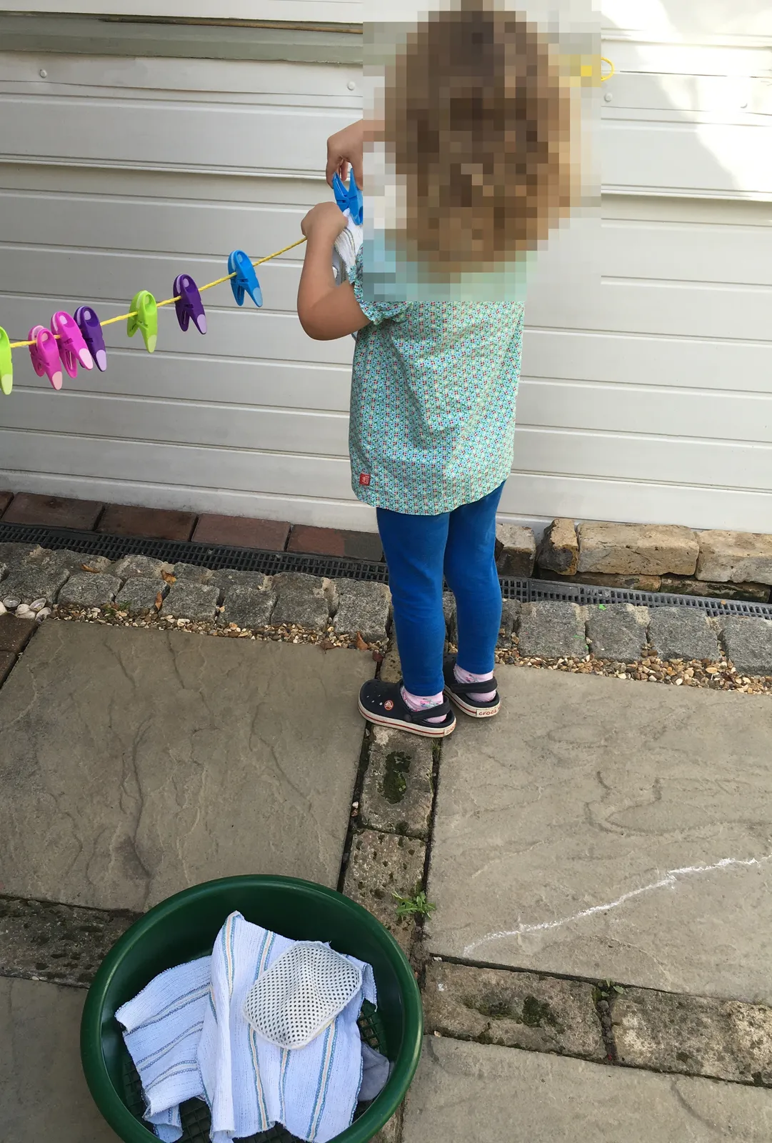Small child carefully clipping cloths onto a miniature washing line.